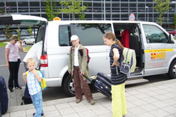 Flughafenzubringer-Fahrzeug mit Gästen vor dem Flughafen